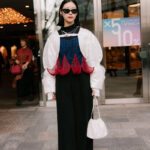 A man in a black and white checkered oversized coat, black pants, and chunky platform boots at Tokyo Fashion Week.