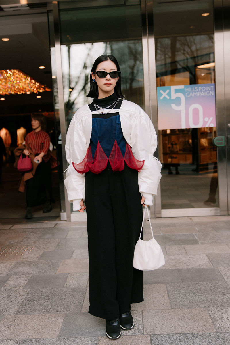 A man in a black and white checkered oversized coat, black pants, and chunky platform boots at Tokyo Fashion Week.