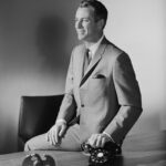 1960s businessman in a gray suit, showcasing Mad Men fashion.