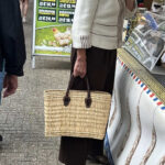 Woman wearing a sweater and carrying a woven bag, showcasing fall fashion trends 2024.