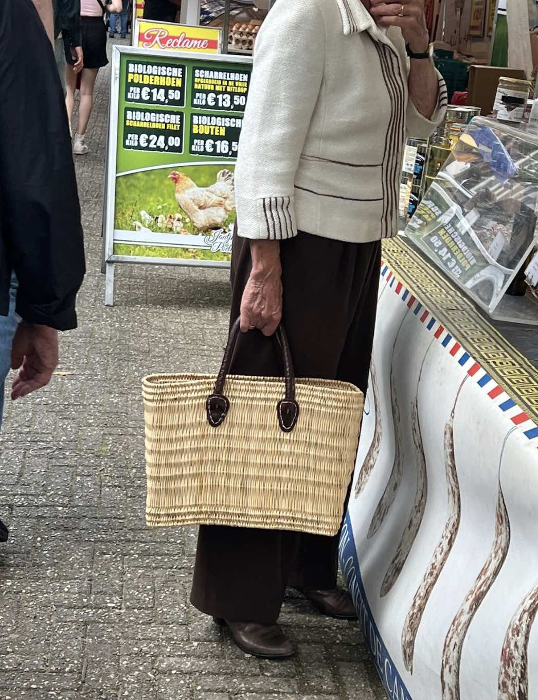 Woman wearing a sweater and carrying a woven bag, showcasing fall fashion trends 2024.