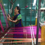 A woman adjusting her loom in India