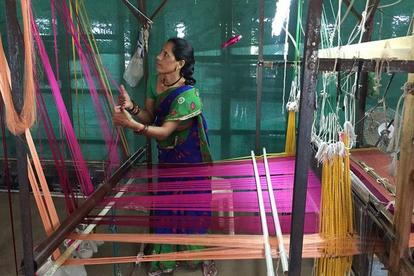 A woman adjusting her loom in India