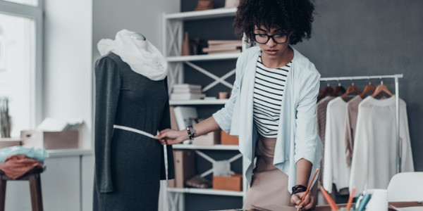 A fashion designer sketching a design in a notebook.