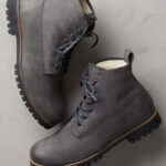 alt text: Close-up of a man's foot wearing a gray Overland Sheepskin Co. Tobias Shearling-Lined Leather Boot with a rugged sole.