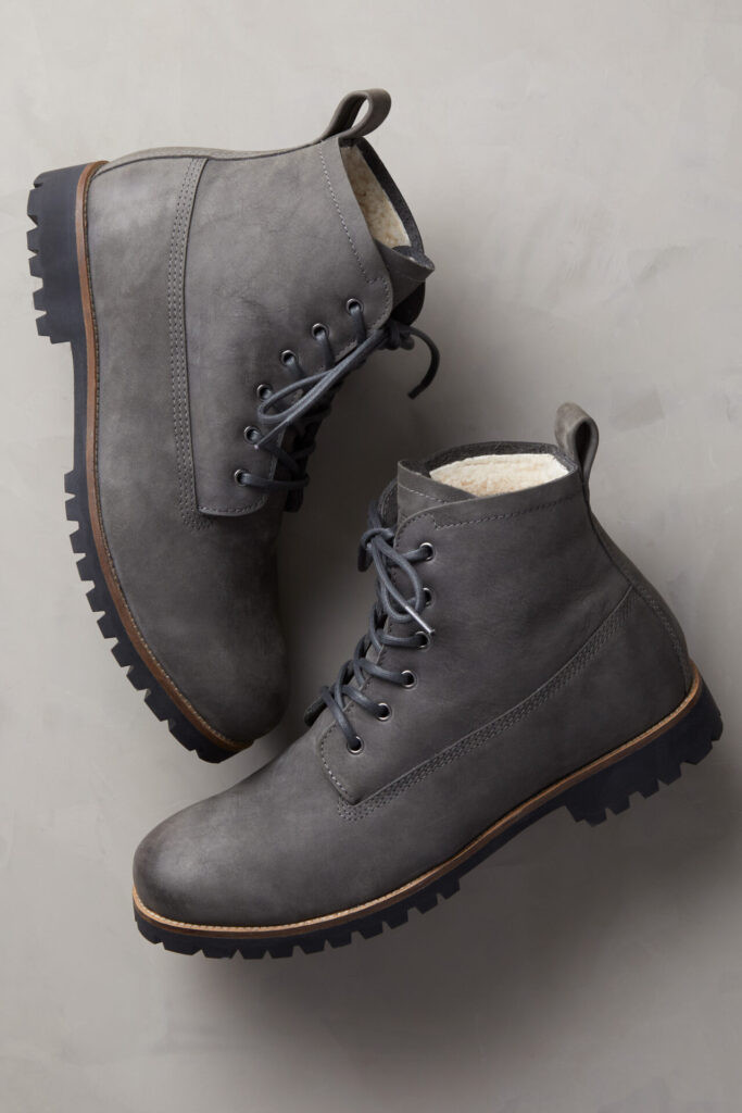 alt text: Close-up of a man's foot wearing a gray Overland Sheepskin Co. Tobias Shearling-Lined Leather Boot with a rugged sole.