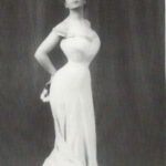 Camille Clifford embodies the Edwardian S-silhouette, showcasing the era's characteristic curved figure with a pronounced bust and hips, achieved through corsetry and fashionable garments.