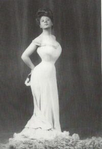 Camille Clifford embodies the Edwardian S-silhouette, showcasing the era's characteristic curved figure with a pronounced bust and hips, achieved through corsetry and fashionable garments.