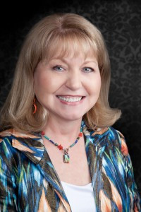 Alt text: Close up photo of a woman with vibrant orange hair styled in short, blunt bangs.