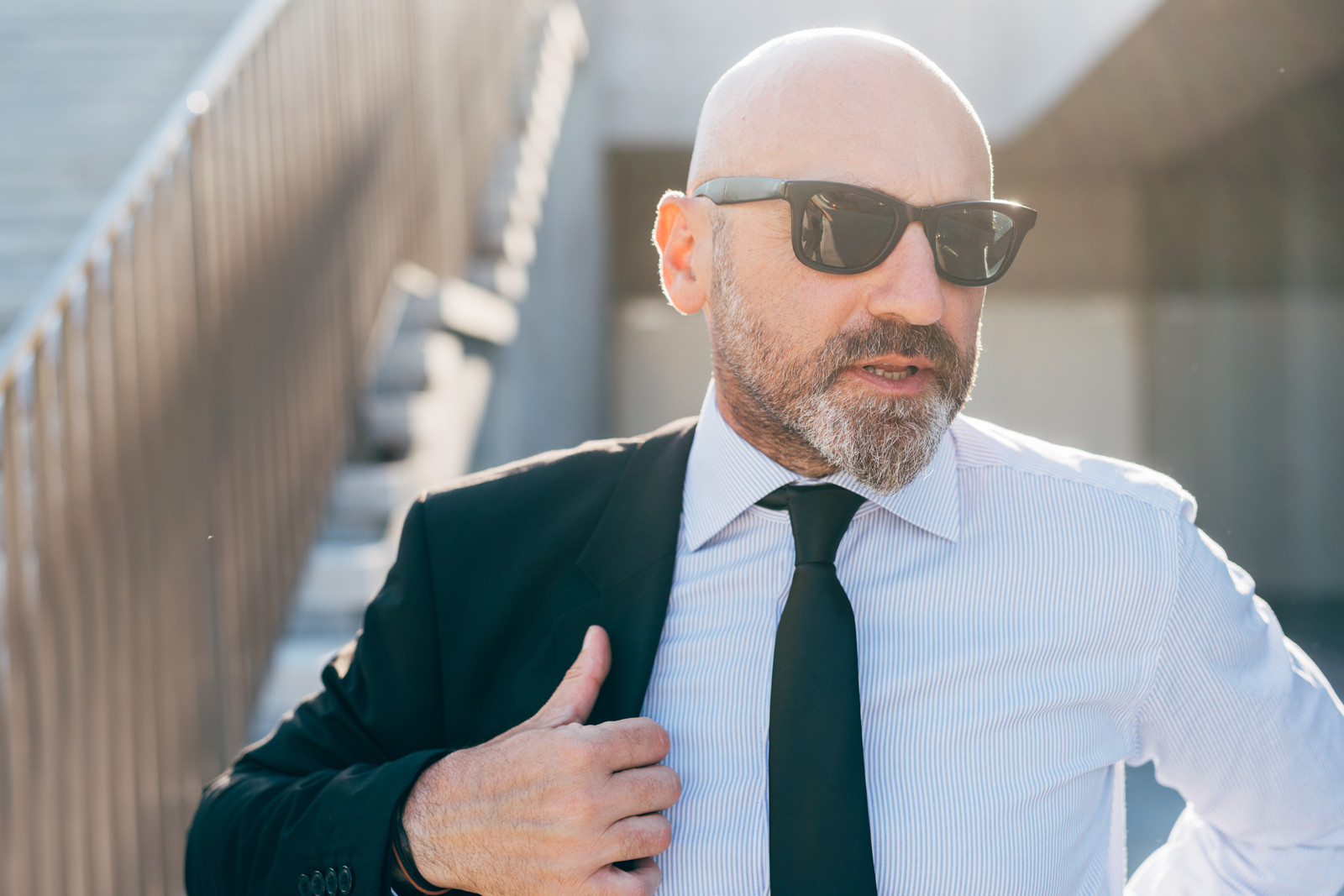 Bald man in sunglasses putting on his coat