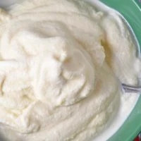 green bowl of homemade vanilla ice cream with spoon