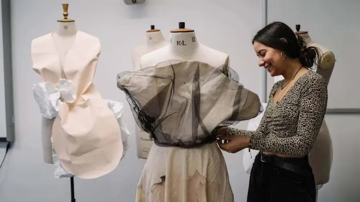 Fashion student skillfully draping fabric on a dress form in a design studio