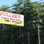 Fuller's Old Fashion BBQ restaurant exterior in Lumberton NC, showcasing its large log cabin style building and prominent signage.