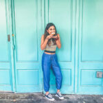 Woman enjoying a beignet in New Orleans, demonstrating a casual fashion style.