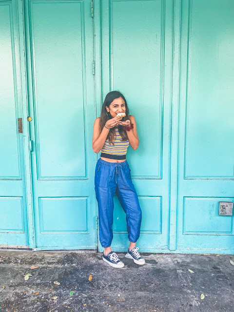 Woman enjoying a beignet in New Orleans, demonstrating a casual fashion style.