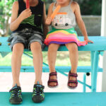 Girl wearing pink sport sandals and a floral skirt.