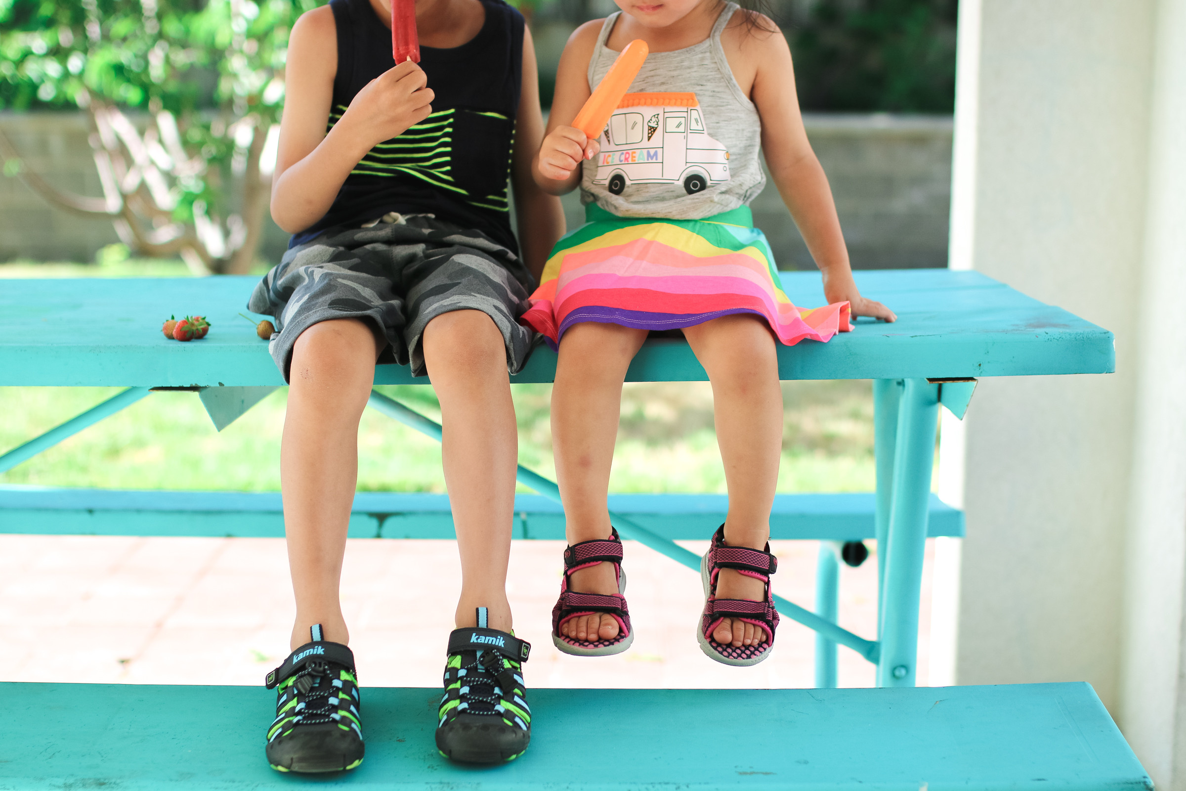 Girl wearing pink sport sandals and a floral skirt.