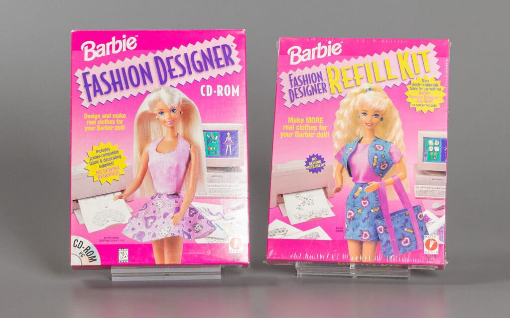 alt text: A young girl playing Barbie Fashion Designer on a computer, focused on creating a new outfit for her doll.