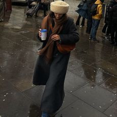 Fashion influencer @_santinaharrison wears a chic and practical look with a shearling hat and long coat.