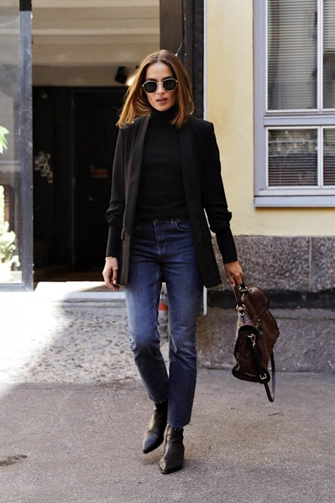 A woman wearing a black blazer, jeans, and heeled boots, showcasing a chic French fashion style.