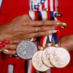 Close-up shot of Florence Griffith Joyner (Flo Jo) showcasing her long, vibrant, and uniquely decorated acrylic nails while competing, highlighting the athlete's iconic nail style in the 1980s black fashion and sports scene.