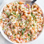 A bowl of classic shrimp salad garnished with fresh herbs.