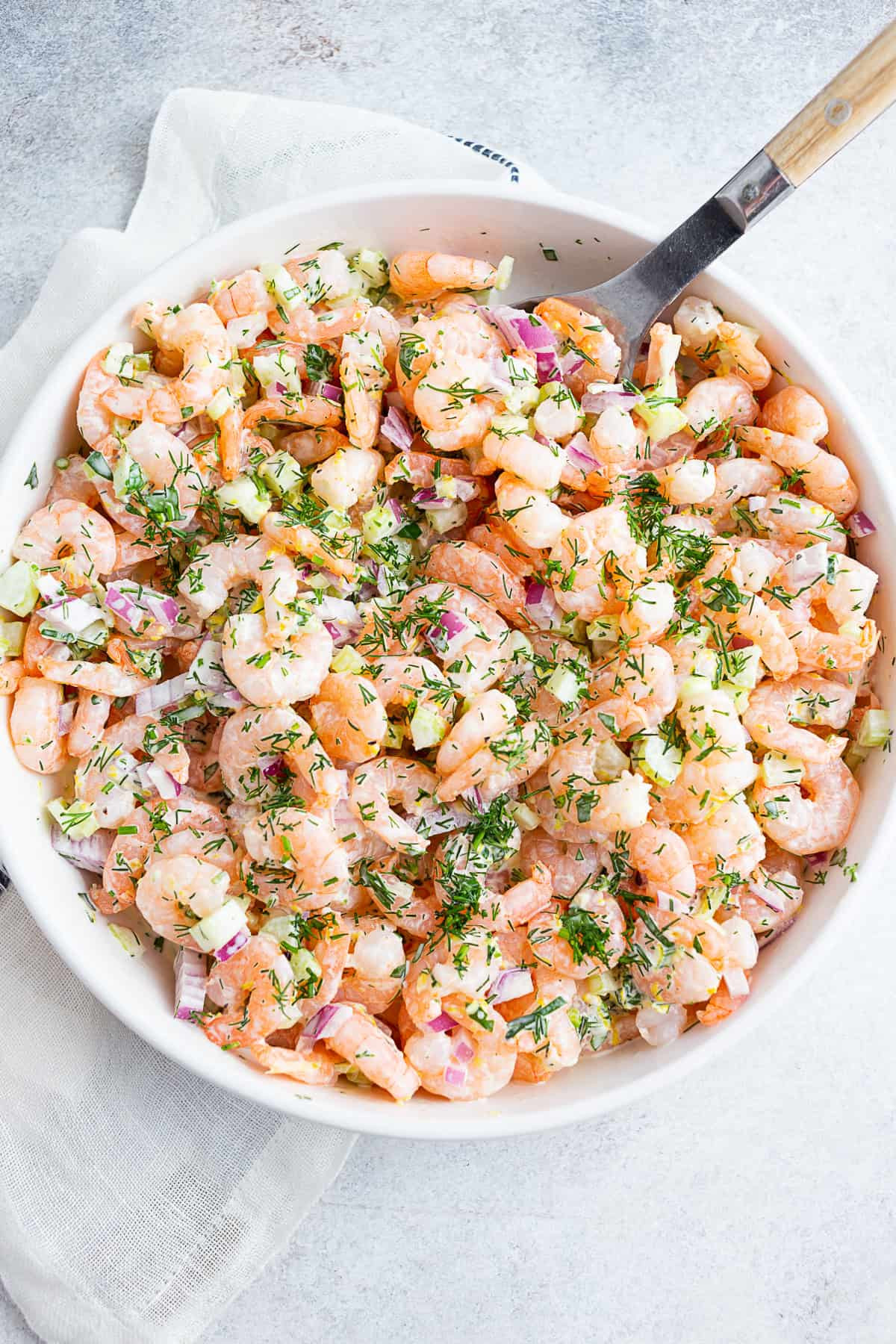 A bowl of classic shrimp salad garnished with fresh herbs.