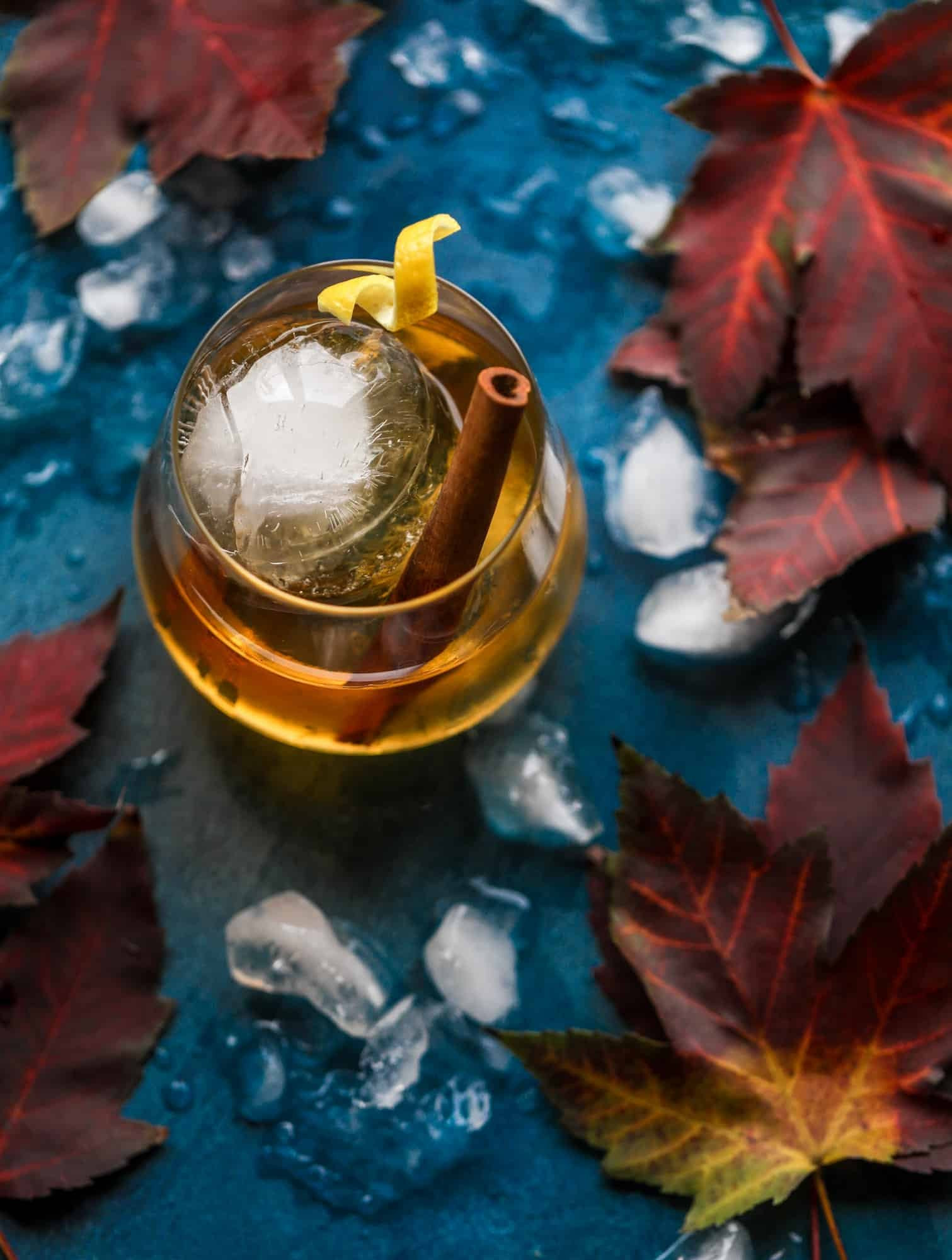 A smoked maple old fashioned cocktail in a rocks glass, garnished with an orange peel.