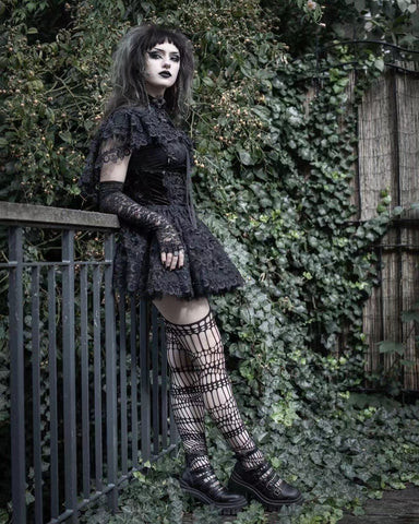 A woman with trad goth makeup, featuring black lipstick, eyeliner, and pale foundation.