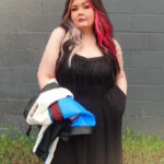 Woman in a black fringed maxi dress, posing in front of a building