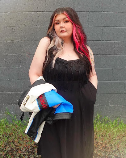 Woman in a black fringed maxi dress, posing in front of a building