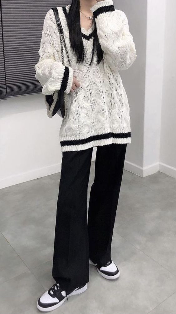 A man wearing a sophisticated Acubi outfit with a loose textured sweater over slacks