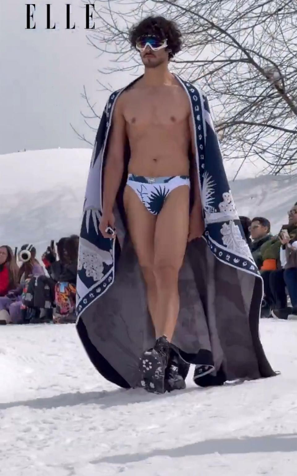Male model strutting on a snow-covered catwalk, scantily dressed, at a fashion show in Kashmir, sparking controversy.