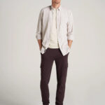 Man standing with hands in pockets wearing linen button shirt and dark pants