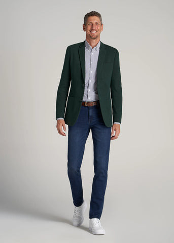 Man appearing to be taking a step forward wearing dark blue jeans and a tall blazer