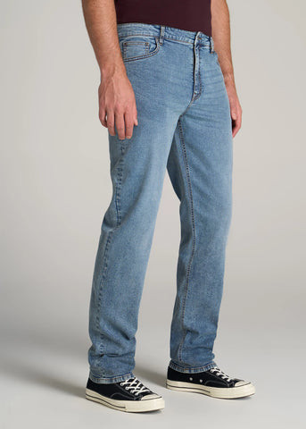 closeup of man standing wearing straight leg, light colored jeans and sneakers