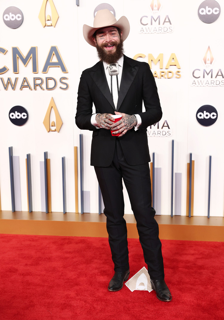 Post Malone at the 57th Annual CMA Awards, sporting a contemporary Western look with a tailored black suit and subtle cowboy-inspired details.
