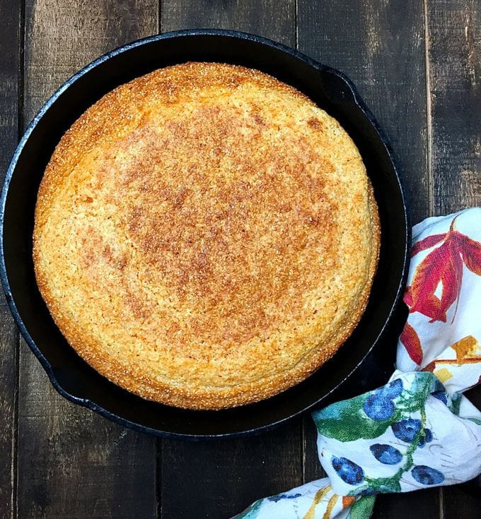 Golden brown cornbread cooling in a cast iron skillet.