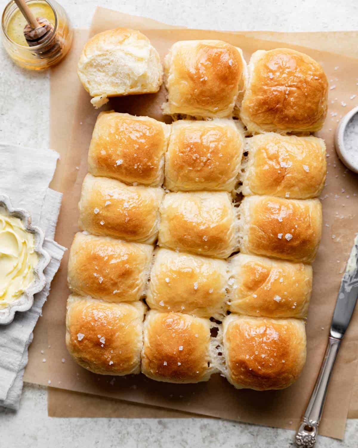 Golden brown old fashioned yeast rolls on a parchment-lined baking sheet, showcasing their fluffy texture and inviting appearance.