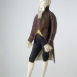 High-waisted coat and light-colored trousers reflecting early 1800s fashion