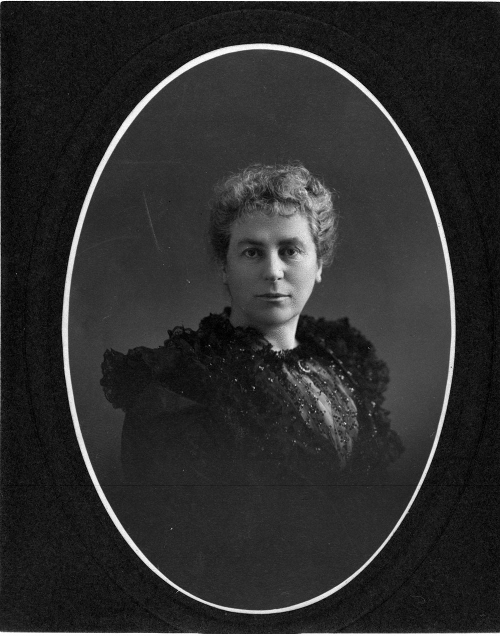 Woman wearing a dress with mutton sleeves and an A-line skirt, showcasing the typical silhouette of the 1890s womens fashion.
