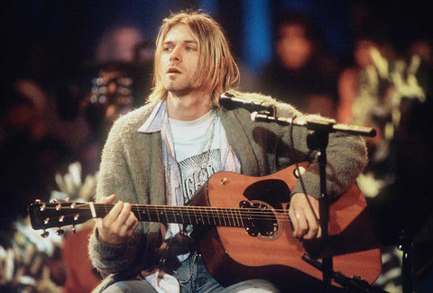 Kurt Cobain's look, a graphic tee layered under a shirt and beige cardigan