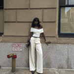 Man wearing a draped top tucked into cream wide-leg trousers, showcasing a sophisticated fashion trend