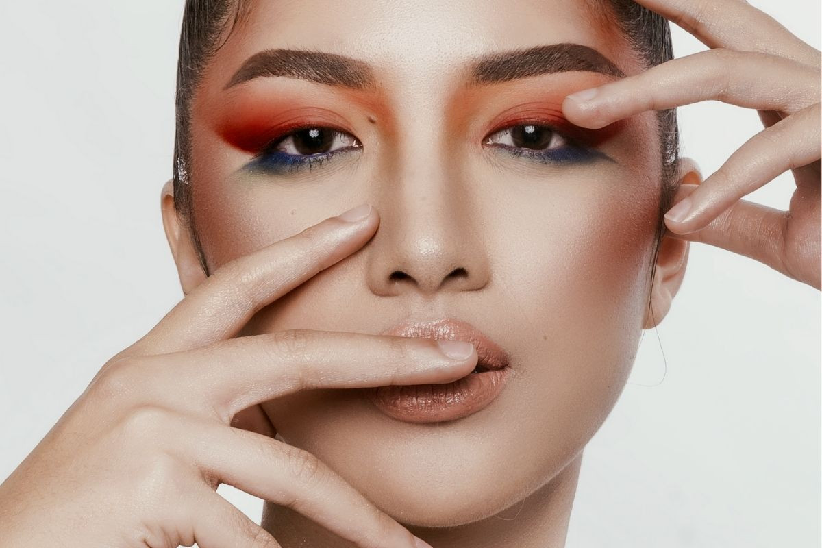 Hands delicately framing a male model's face, highlighting his features and adding depth to the shot