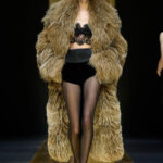 Dolce & Gabbana Fall 2024 Ready-to-Wear showcases a luxurious fur coat, embodying the trend of Texture Triumph with voluminous proportions and opulent design
