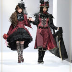 Midori Fukasawa and Akira walking down runway in matching red and black lolita and ouji sets from Alice and the Pirates, showcasing gothic and pirate themes