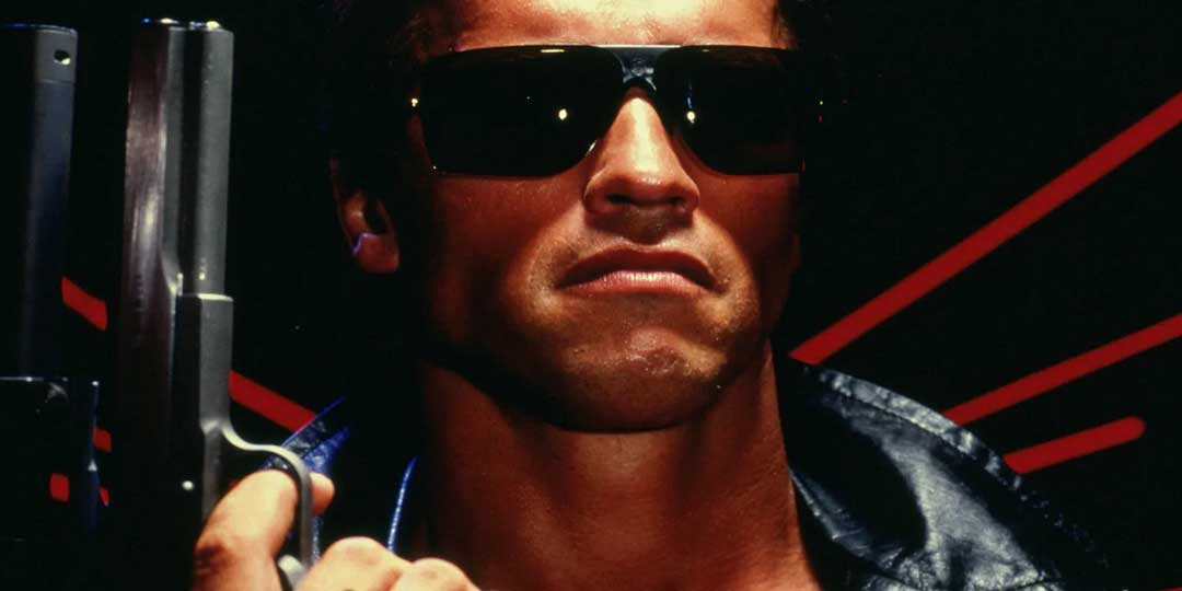 Arnold Schwarzenegger in Terminator wearing dark black sunglasses holding a gun