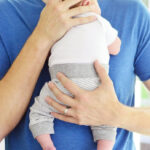 A father tenderly cradles his newborn baby boy against his chest, symbolizing the profound bond and love between them