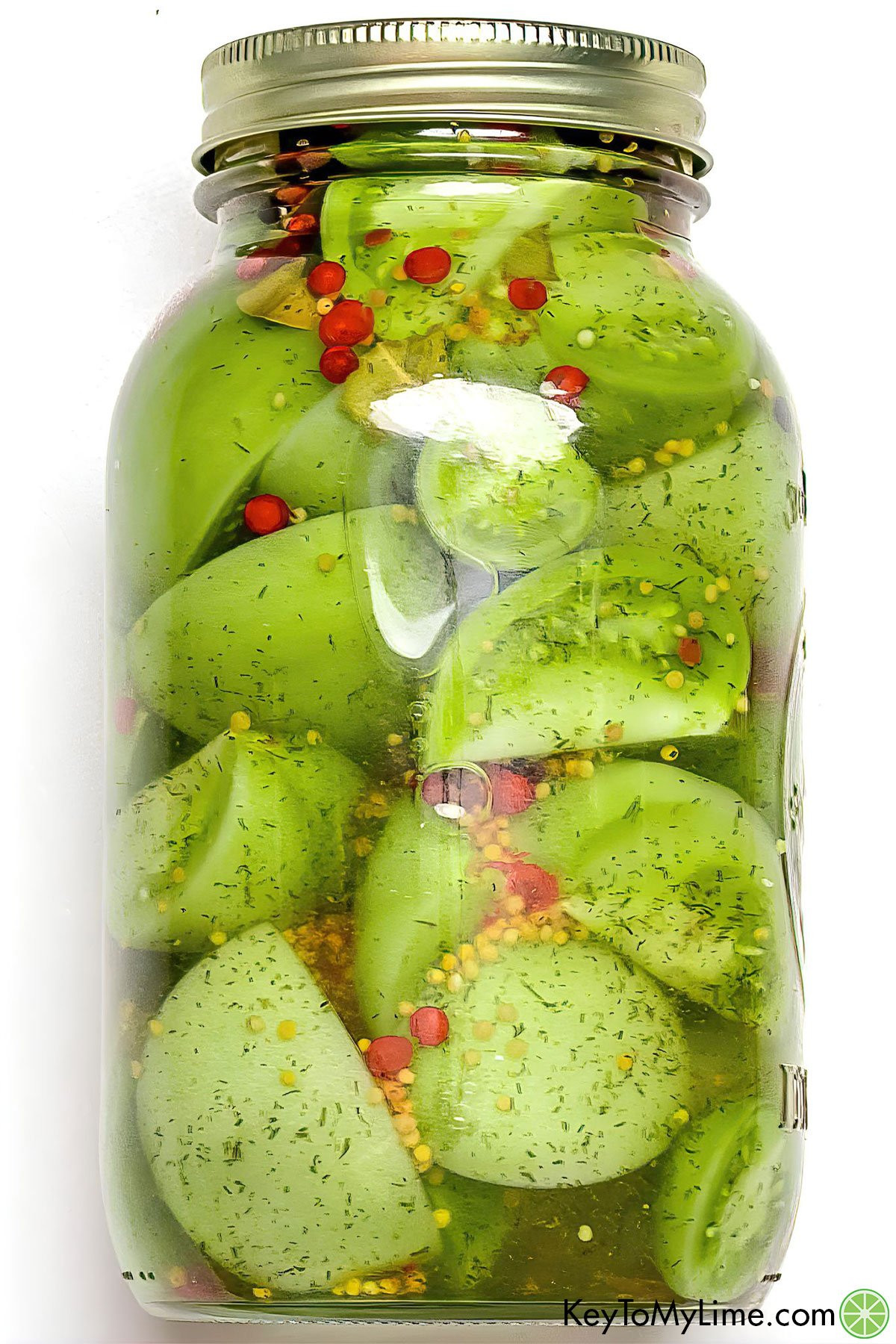 A jar filled with sliced and pickled green tomatoes.