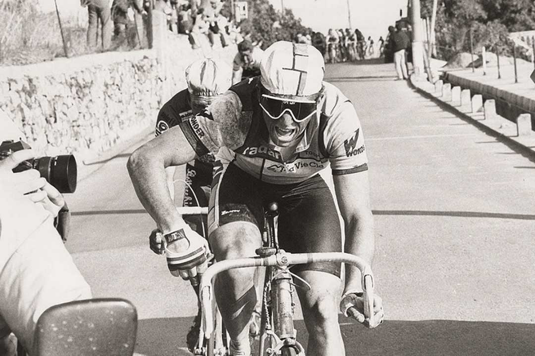 Black and white photograph of male cyclist on his bike wearing Oakley sunglasses